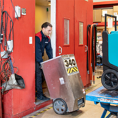 Jon-Don repair technician wheeling a dehumidifier out of a red testing chamber